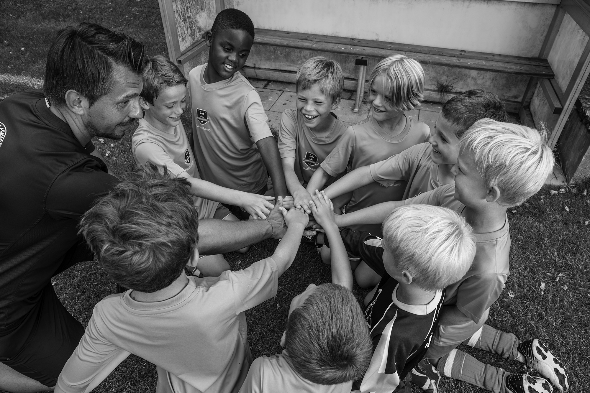 Overhead view of a coach and young soccer players joining hands on the grass